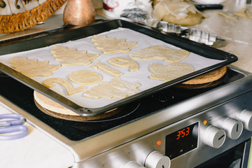 Making Christmas gingerbread at home, shapes from dough are cutted with cutters, such as trees,...