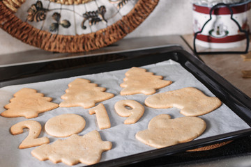 Making Christmas gingerbread at home, shapes from dough are cutted with cutters, such as trees,...