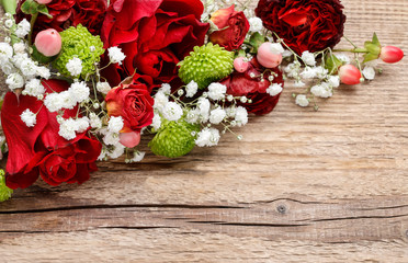 Floral arrangement with orchids, roses and carnations on wooden background