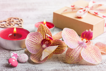 Orchids, craft gift box and lit candles