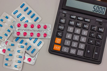 Drugs in the form of tablets lie next to the calculator. on the calculator figure million