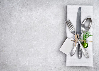 Christmas table setting background with copy space. Concrete background with napkin, silverware and rosemary branch. Cutlery with fork, knife and spoon. Top view, christmas decoration.