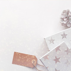 A real photo of white Christmas card with a pinecone, white presents in stars with a label. Copy space with snowflakes
