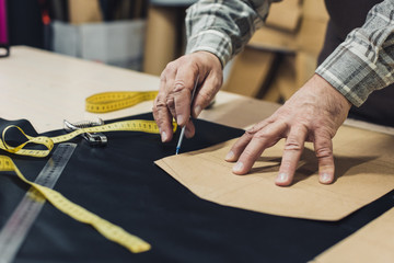 Obraz premium cropped image of male leather handbag craftsman working at studio