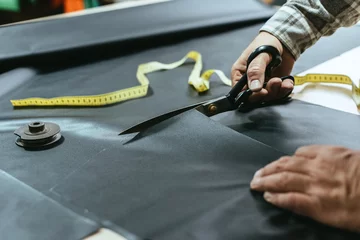 Deurstickers cropped image of male handbag craftsman cutting leather by scissors at workshop © LIGHTFIELD STUDIOS