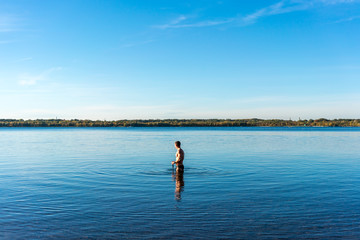 Fototapeta na wymiar Sexy Mann mit Schwimmbrille in einem blauen See kurz vorm Schwimmen