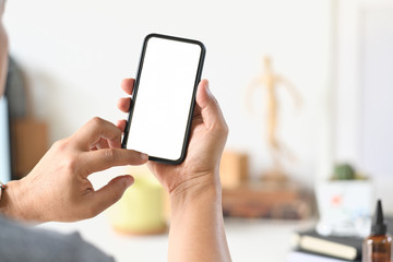 Closes-up male hand using mobile smart phone at desk workspace