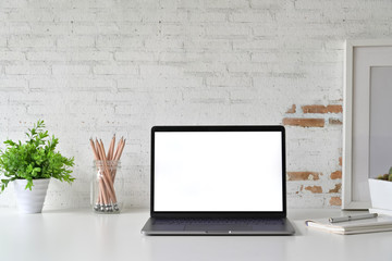 Workspace with blank white screen laptop on loft desk.