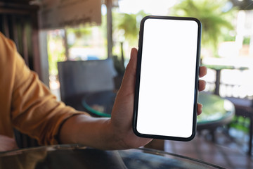 Mockup image of a woman holding and showing black mobile phone with blank white desktop screen
