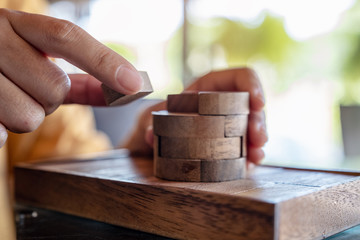 Closeup image of people playing and building round wooden puzzle game