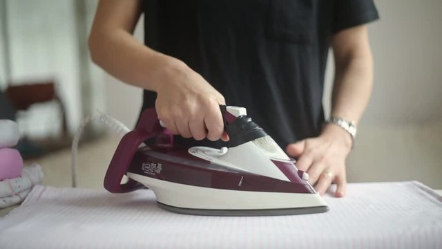 Close up footage of woman ironing clothes at home.
