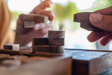 Closeup image of two people playing and building round wooden puzzle game