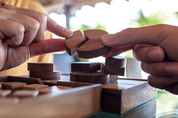 Closeup image of two people playing and building round wooden puzzle game