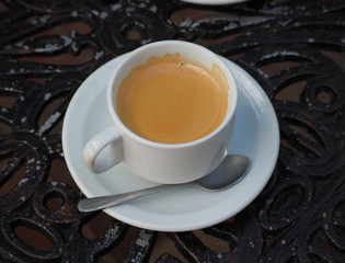 A cup of coffee on a metal decorative table