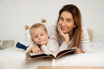 A young mother teaches her four-year-old daughter to read fairy tales before going to bed. A woman brings up a girl at home alone