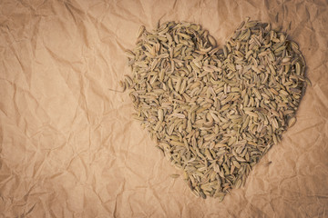 Fennel dill seeds heart shaped on paper surface