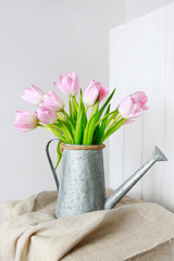 Bouquet of pink tulips in silver watering can.