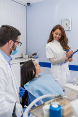 High angle view of dentist examining girl with dental equipments