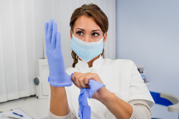 Beautiful female doctor - dentist putting surgical gloves