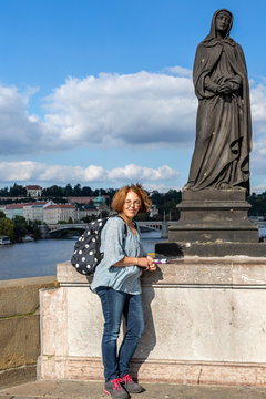 Female backpacker tourist posing next to a statue on Charles bridge i Prague Czech Republic.