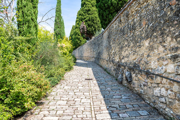 Via San Damiano street, road, stone walkway, path pedestrian way at monastery in Assisi, Italy with wall, old, ancient, antique architecture, Italian landscape, cypress trees in summer