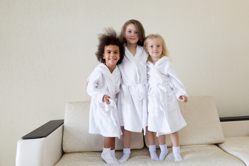 Three funny girls in white coats. Girls girlfriends of different nationalities are in white coats and socks.