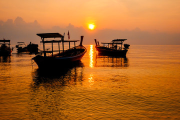The sun is rising with the new morning and the boat in the sea.