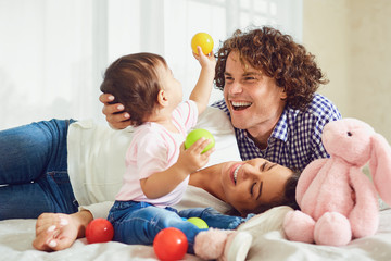Happy family playing with the baby in the room. Young mother and