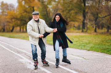 Happy pension. Active sport old people. The old man goes on rollers with his young daughter in the autumn park. Comic dance, a parody of the Swan Lake.
