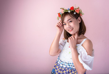 Asian girl with acne-free face and freckles ,Which is the problem of teens.Young woman pose on a pink background and in the hand holding a beautiful bouquet.