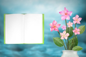 Beautiful live clematis bouquet bouquet in porcelain vase with notepad with place for your text on left on colored sky with clouds background.