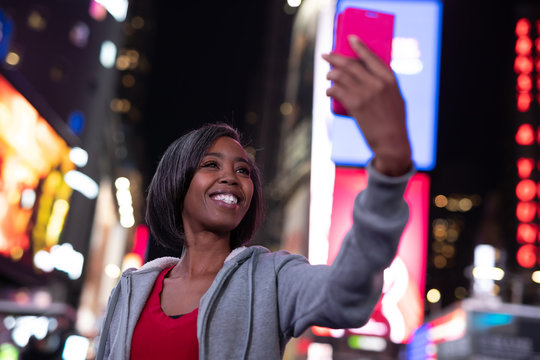 Woman in city at night taking selfie picture