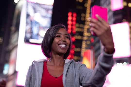 Woman in city at night taking selfie picture