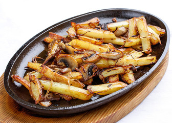 Fried potatoes with onions and mushrooms. On a cast-iron frying pan.