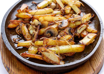 Fried potatoes with onions and mushrooms. On a cast-iron frying pan.