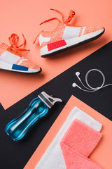 Flat lay with sneakers, sport bottle, towel and headphones on black background