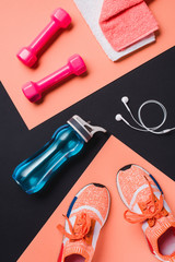 Flat lay with sneakers, dumbbells, sport bottle, towel and headphones on black background