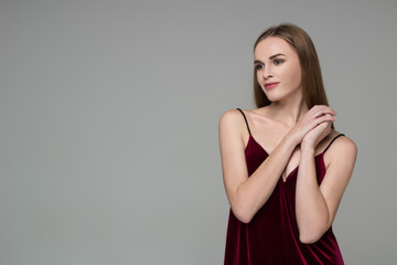 Young blond girl in dark red dress showing emotions: pleasure