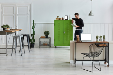 Man ,s working from home. White living room green cabinet and dining table style. Laptop and table close up concept.