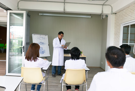 Professor hold the laptop while teaching about the fish anatomy to young scientists and veterinarians doctor. Shooting picture from the back of room. Selective focus.
