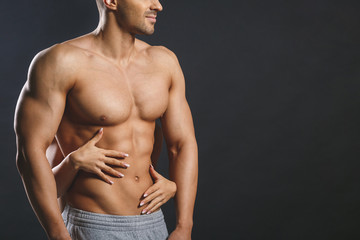 Love and sex concept - female hands touching muscular man isolated over grey background. Sexy fit...