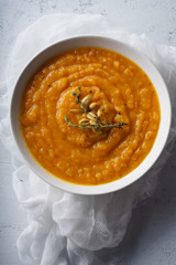 Pureed pumpkin soup with seeds and thyme. Warm food concept, dieting. Concrete background, overhead view.