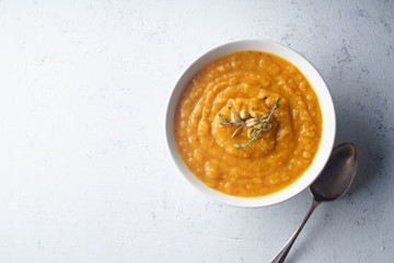 Pureed pumpkin soup with seeds and thyme. Warm food concept, dieting. Concrete background, overhead view. Copy space
