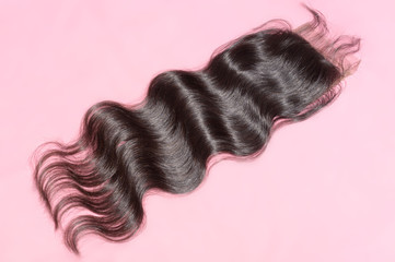 Body wavy black human hair weaves extensions lace closure upon pink background