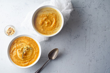 Pureed pumpkin soup with seeds and thyme. Warm food concept, dieting. Concrete background, overhead view. Copy space
