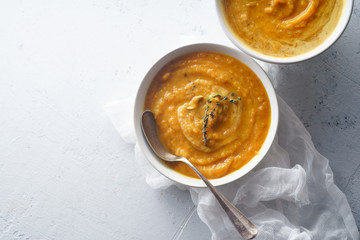 Pureed pumpkin soup with seeds and thyme. Warm food concept, dieting. Concrete background, overhead view. Copy space