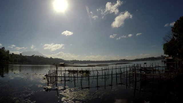 Sampaloc Lake, San Pablo City, Laguna, Philippines - February 25, 2018: Rotting bamboo fish cage built along mountain lake shore, reflection artistic background
