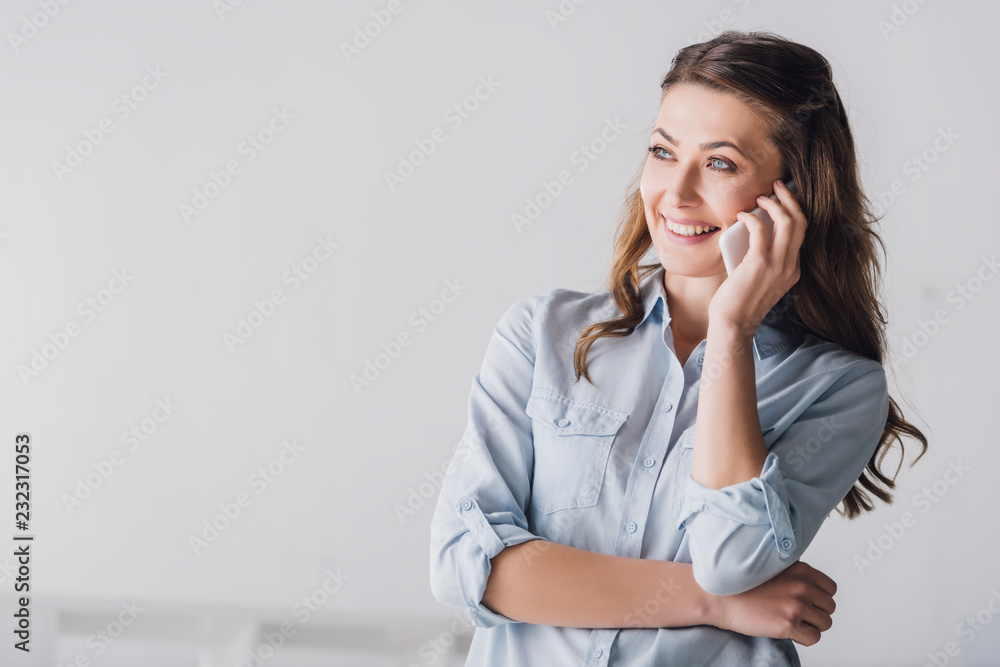 Wall mural close-up portrait of smiling adult woman talking by phone and looking away