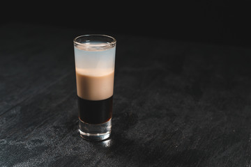 Bartender pours alcoholic drink into small glasses on bar. Colorful cocktails at the bar. Colorful shots at the club. Alcoholic drink in different colors. Nightlife scene. Shots at the bar table.