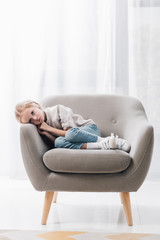 depressed little child lying in armchair alone